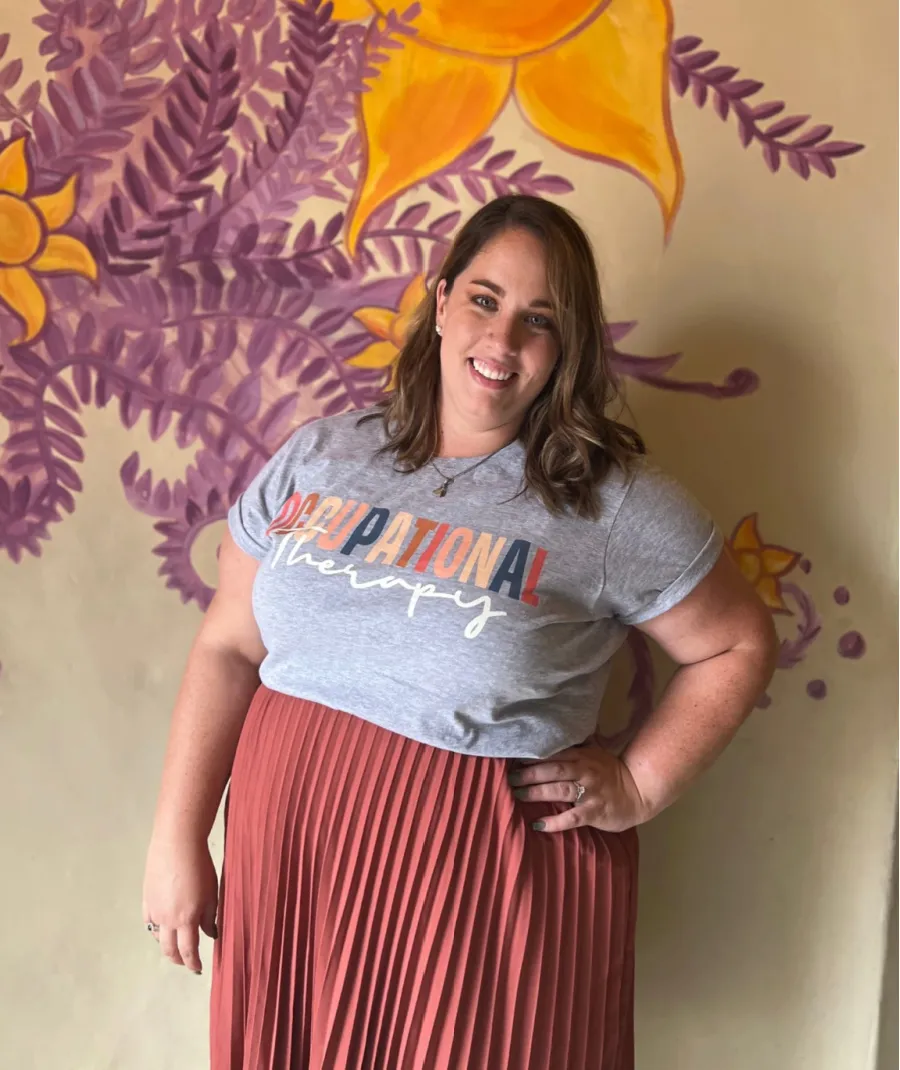 Samantha standing against a wall with orange skirt on