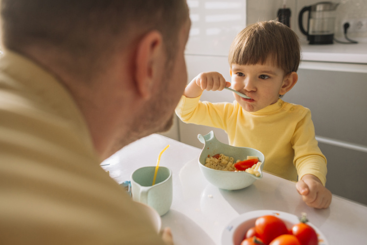 Therapist's hand on toy showing child how to manipulate the toy