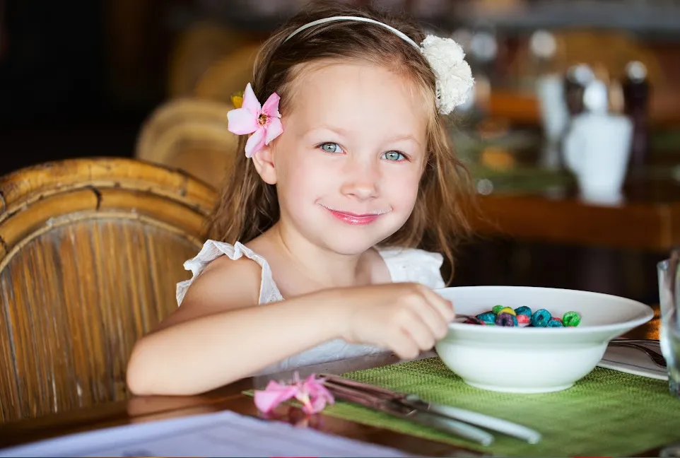 little girl eating a bowl of something at the table