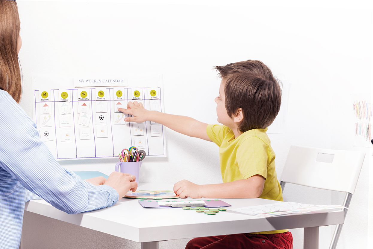 Child sitting at a table pointing to a calendar