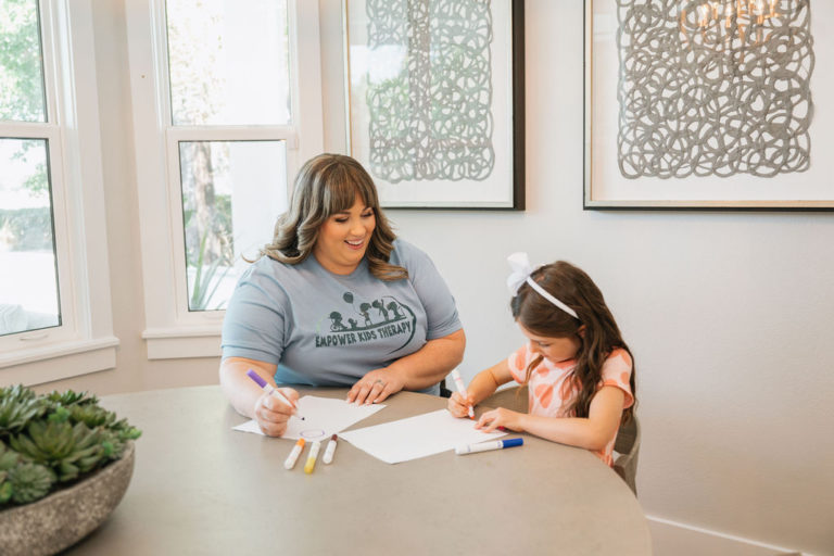 Female teacher at the dining table with a female student writing on paper