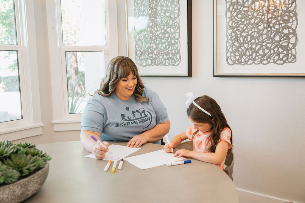 Female teacher at the dining table with a female student writing on paper