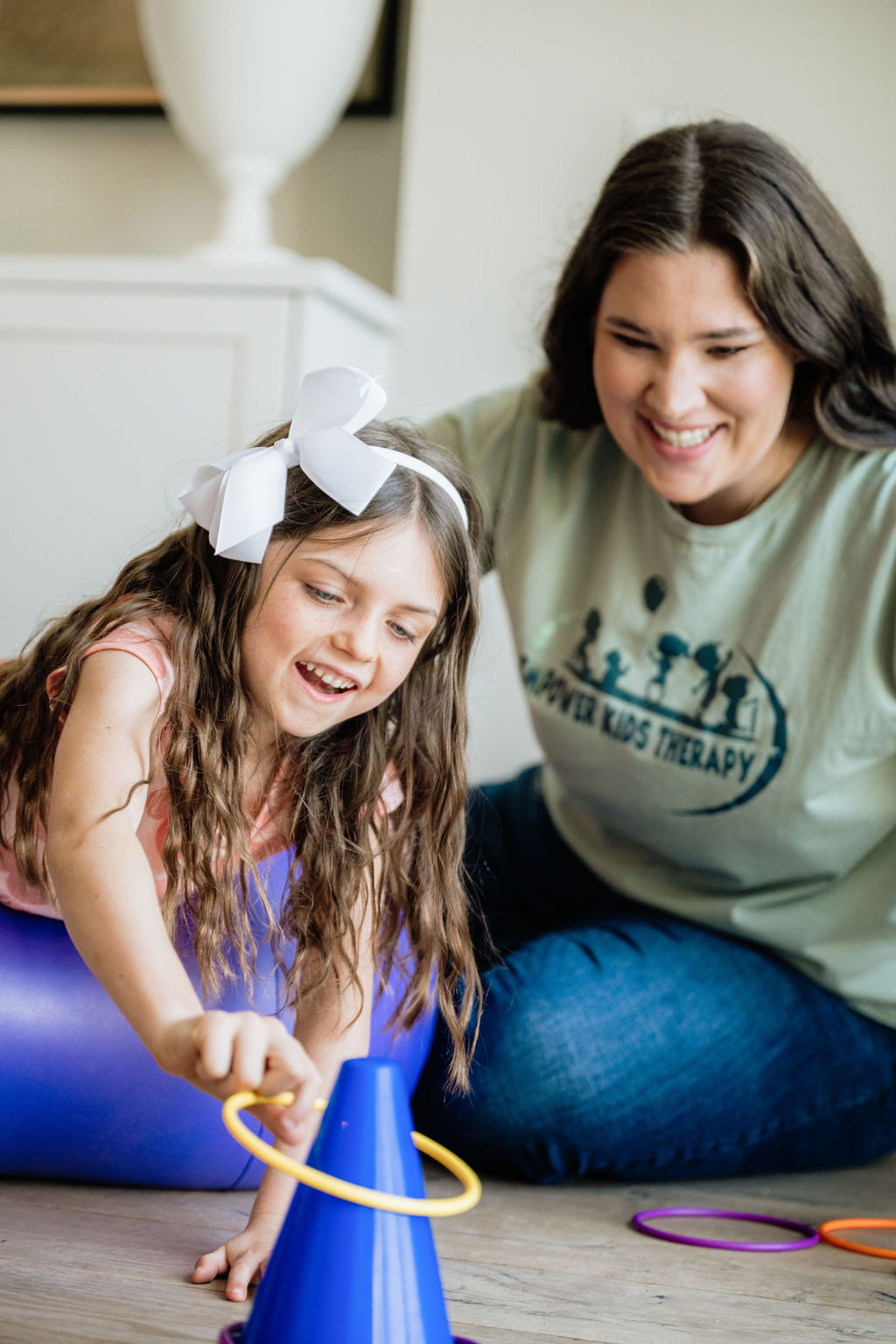 Therapist's hand on toy showing child how to manipulate the toy